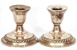 Pair of white metal loaded dwarf candlesticks with urn shaped socles on circular stepped gadrooned