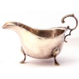 George V silver sauce boat with card cut rim and leaf capped flying scroll handle on cast hoof feet,