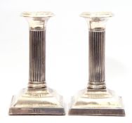 George V silver small candlesticks, Corinthian columns to a plain square stepped base (loaded), 12