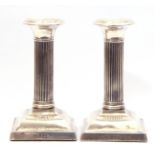 George V silver small candlesticks, Corinthian columns to a plain square stepped base (loaded), 12