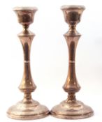 Pair of George VI silver candlesticks, integral urn shaped sconces above waisted columns on weighted