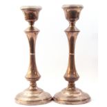 Pair of George VI silver candlesticks, integral urn shaped sconces above waisted columns on weighted