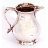 George V silver cream jug in the sparrow-beak style, having a plain round bellied body, a capped