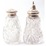 Two moulded and cut glass sifters both with pierced silver lids, 14cm and 12cm respectively, (2)