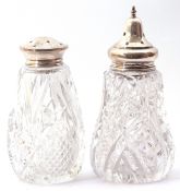 Two moulded and cut glass sifters both with pierced silver lids, 14cm and 12cm respectively, (2)