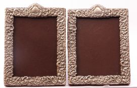 White metal photograph frames of rectangular form, embossed with flowers and scrolls, both with