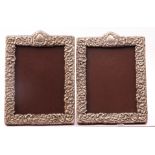 White metal photograph frames of rectangular form, embossed with flowers and scrolls, both with