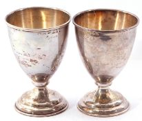 Two sterling wine goblets having plain round tapering bodies with reeded borders, each sitting on