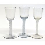 Group of three 18th century wine glasses all with air twist and central gauze on conical feet, (