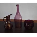 Group of three purple coloured glass wares comprising a bowl and a ewer and further glass bottle,