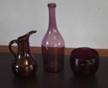 Group of three purple coloured glass wares comprising a bowl and a ewer and further glass bottle,