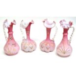 Group of pink glass ewers with rope twist effect handles, all with floral designs on a shaded pink