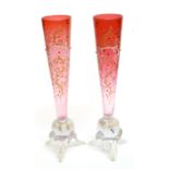 Pair of tapered cranbery glass vases raised on three feet, the tapered bodies decorated with a