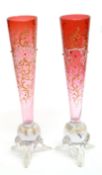 Pair of tapered cranbery glass vases raised on three feet, the tapered bodies decorated with a