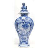 Dutch Delft vase and cover with dog finial, the vase painted with a landscape scene and flowers,
