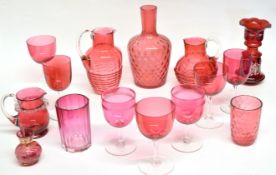 Collection of cranberry glass wares including six wine glasses of various sizes, two jugs, small