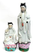 Two Chinese porcelain models of Guan Yin decorated in typical fashion, both on green bases,