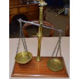 Set of vintage brass beam scales on a mahogany plinth, 48cm wide