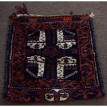 Caucasian camel bag decorated on one side with geometric designs on a mainly dark blue and puce