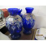 TWO BALUSTER BLUE GLASS VASES OVERLAID WITH PAINTED FLORAL DECORATION AND FURTHER BLUE GLASS LUSTRE