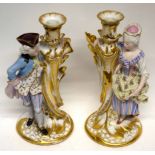 Pair of late 19th century Paris porcelain candlesticks, richly gilded, flanked by a lady and gent in