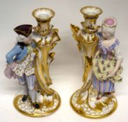 Pair of late 19th century Paris porcelain candlesticks, richly gilded, flanked by a lady and gent in