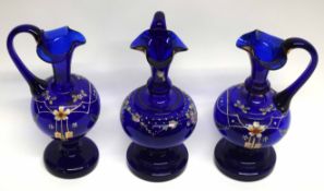 Group of three blue glass ewers, all with floral decoration