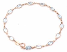Modern 9ct gold bracelet featuring 14 oval faceted pale blue pastes, 19cm long