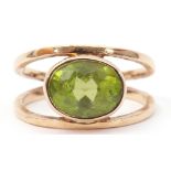 9ct gold peridot ring, the oval faceted peridot bezel set between split plain polished shoulders,