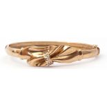 Modern 375 stamped hinged bracelet centring a tied ribbon and set with five small paste stones, g/