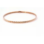 9ct gold bangle with a continuous stylised engraved design, 7cm diam, 3.6gms