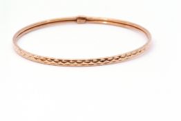 9ct gold bangle with a continuous stylised engraved design, 7cm diam, 3.6gms