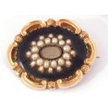 Early Victorian gold, black enamel and seed pearl mourning brooch, the centre with a glazed panel of