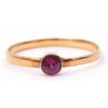 Antique 22ct gold ring with a small circular pink ruby in a collet setting, to a plain polished