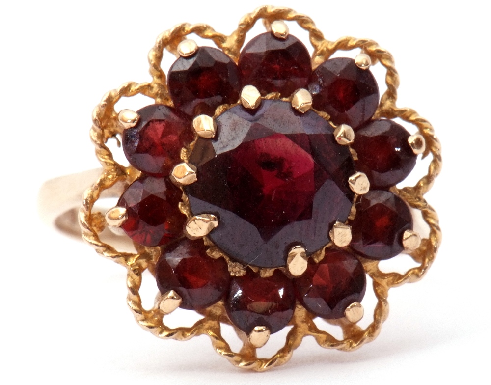 9ct gold garnet cluster ring, the central faceted round garnet within a small garnet surround,