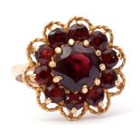 9ct gold garnet cluster ring, the central faceted round garnet within a small garnet surround,