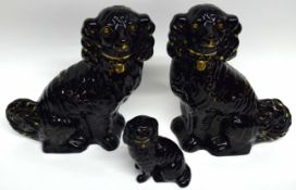 Three Staffordshire spaniels, all black painted with gold decoration, the largest 32cm high