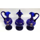 Group of three blue glass ewers, all with floral decoration
