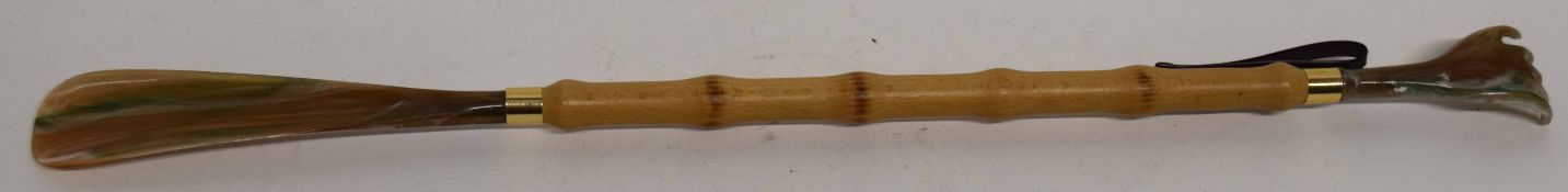 Wooden shoe horn with back stretcher at one end in plastic holder