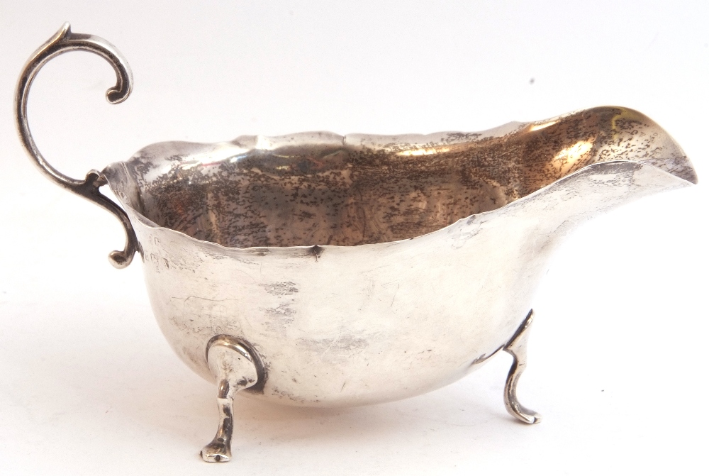 George VI silver sauce boat with shaped rim and capped flying scroll handle, on three cast hoof - Image 3 of 3