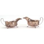 Pair of George VI silver sauce boats each with card cut rims and scroll handles standing on three