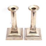 Pair of George V silver candlesticks of plain circular tapering columns, applied with card cut