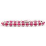 Ruby and diamond set line bracelet featuring 24 oval faceted rubies, each raised within a small