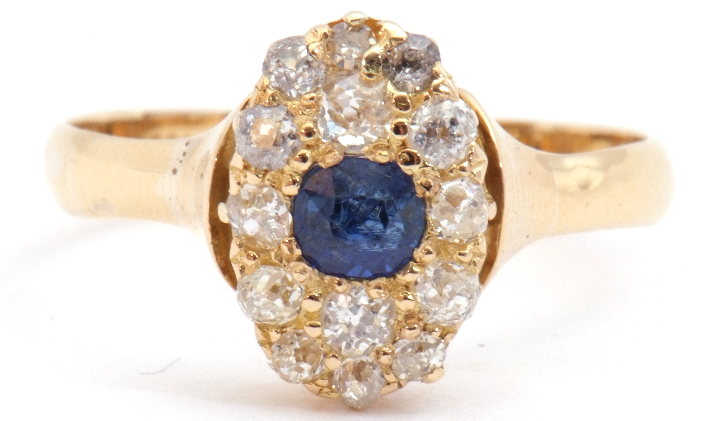 Sapphire and diamond cluster ring, the oval shaped design centring a round cut sapphire and 14 small