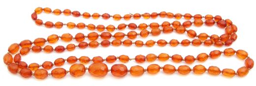 Edwardian long graduated cognac amber bead necklace, a single row of oval shaped faceted beads, 24mm