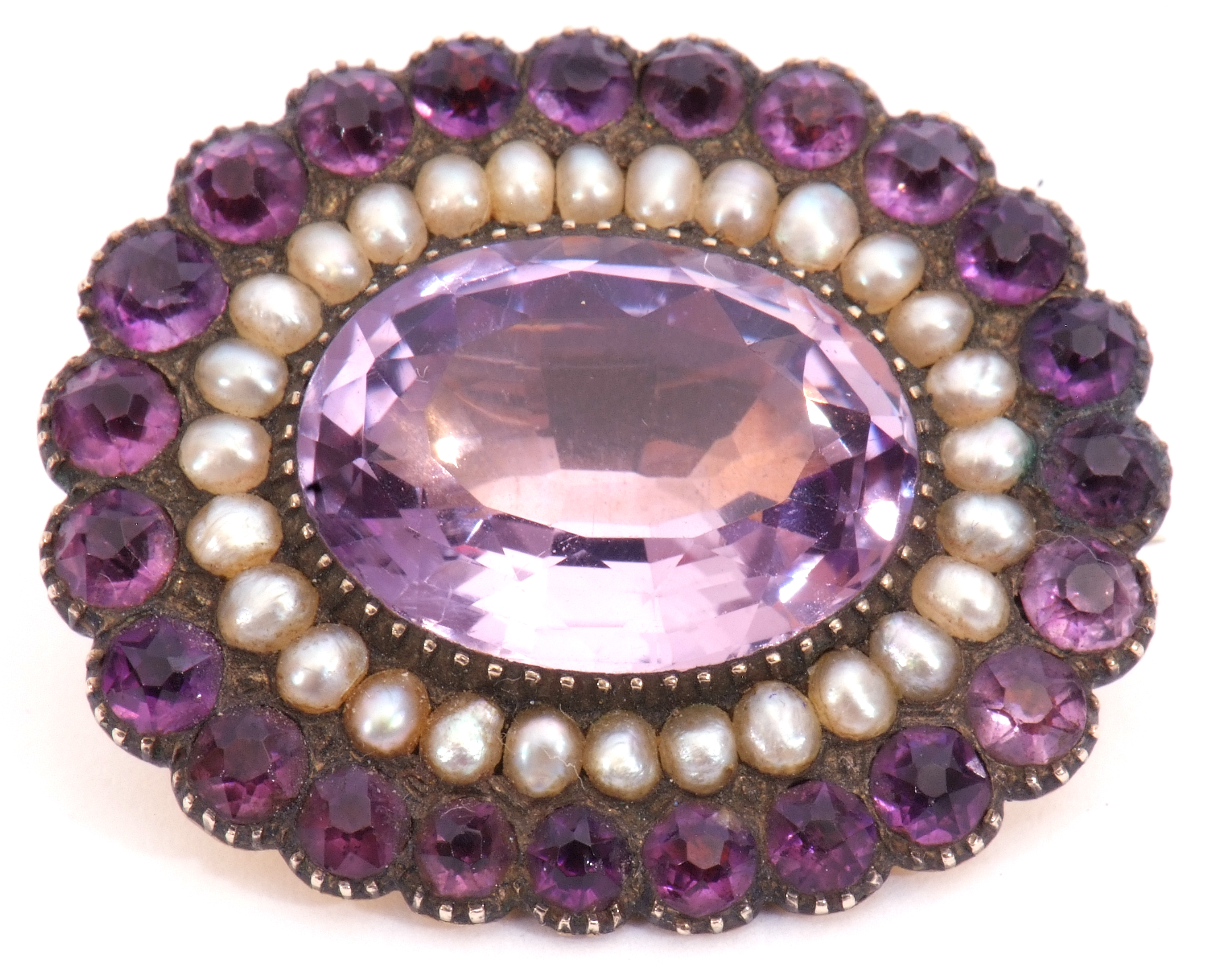 Victorian amethyst and seed pearl brooch, the large oval faceted amethyst 17mm x 12mm, within a seed