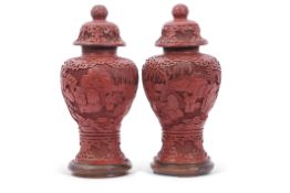 Pair of cinnabar style vases and covers, 24cm high