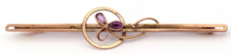 9ct stamped amethyst brooch of open work design, centring an amethyst set flower (one stone missing)