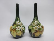 Pair of Lambeth Doulton faience vases by Kate Rogers of bottle shape, the green ground decorated