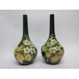 Pair of Lambeth Doulton faience vases by Kate Rogers of bottle shape, the green ground decorated